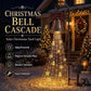 Bronze Christmas bell with red bow and evergreen sprigs lit with cascading warm strands in front of a decorated porch