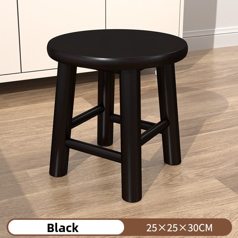 Round leg wooden stool in black finish standing on a pale laminate floor