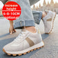 Man walking in light gray suede low top lace up sneakers with a taupe stripe on a paved street