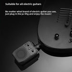 Black plug in mini guitar amp pushed into the output jack of a black electric guitar