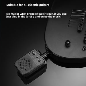 Black plug in mini guitar amp pushed into the output jack of a black electric guitar