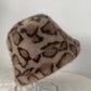 Taupe leopard print plush bucket hat with brown spots on a clear stand
