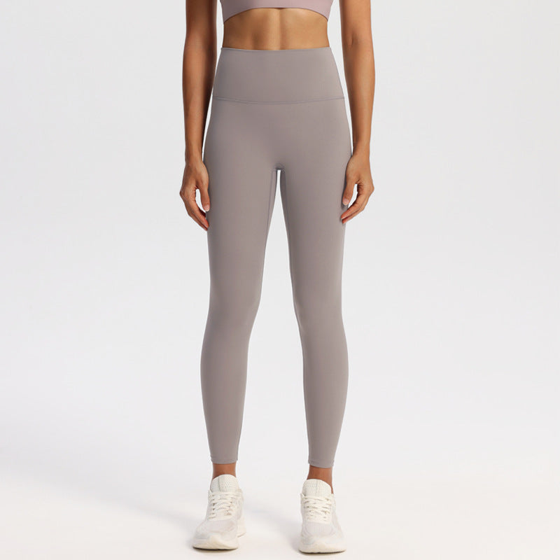 Wide high-rise waistband yoga leggings, nylon spandex knit, worn against a studio wall