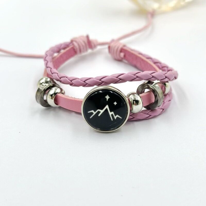 Pink braided cord bracelet with a sun charm and silver tone beads on a wrist