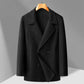 Black double faced wool overcoat shown flat on a wooden hanger, double breasted front with welt pockets