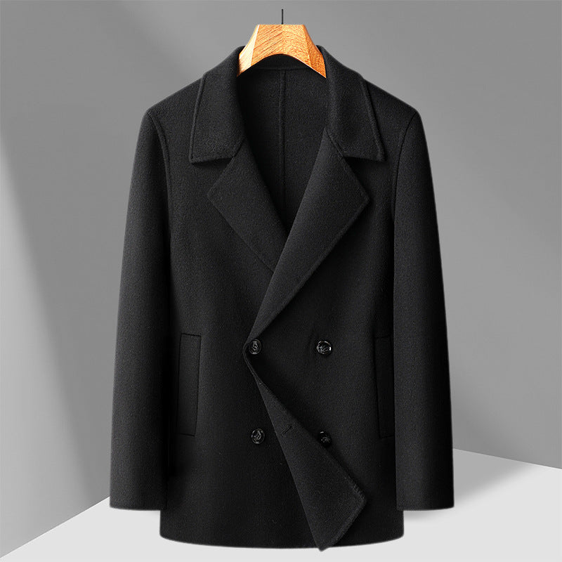 Black double faced wool overcoat shown flat on a wooden hanger, double breasted front with welt pockets