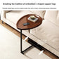 Walnut top C shaped table beside a beige sofa, legs shown sliding under the sofa frame