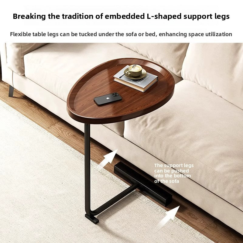 Walnut top C shaped table beside a beige sofa, legs shown sliding under the sofa frame