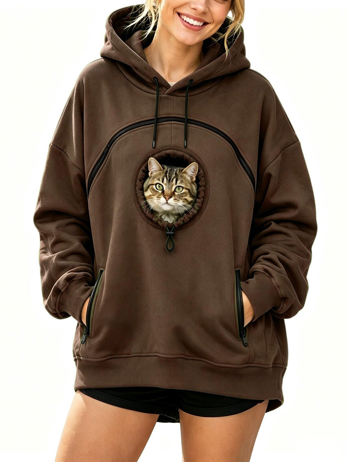 Brown oversized fleece hoodie on a woman with a cat looking out of the round drawstring pocket on the chest