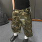 Angled view of the loose camo cargo shorts with a side cargo pocket, a rip and a navy patch on the leg