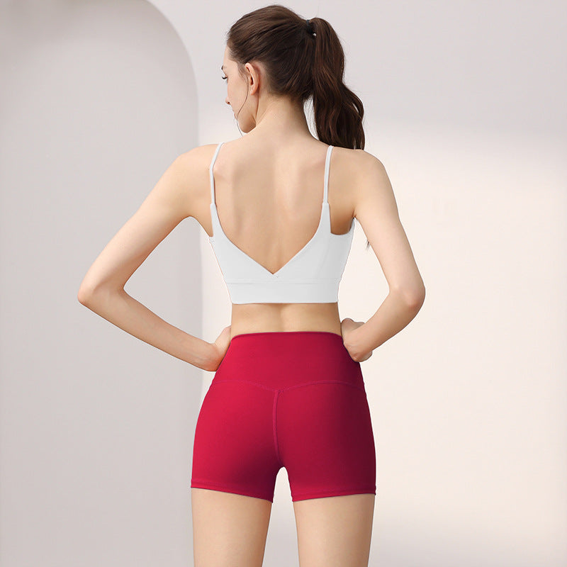 Back view of a woman in a white V-back sports bra and raspberry red high-waist shorts set, size XL option