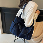 Dark blue denim shoulder tote carried on the shoulder, twin straps and soft slouching washed denim body