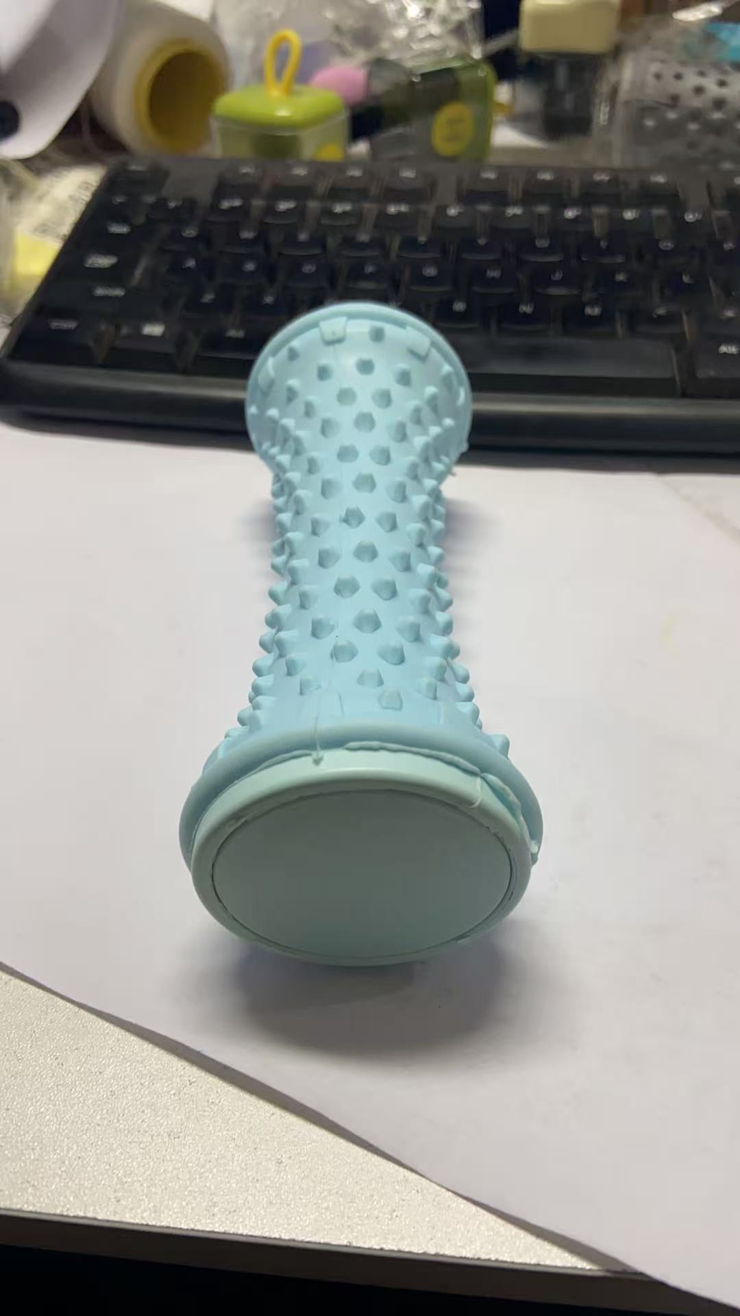 Light blue nubbed foot roller standing upright on a desk beside a keyboard