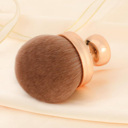 Rose gold handle mushroom head makeup brush with brown synthetic bristles on cream silk