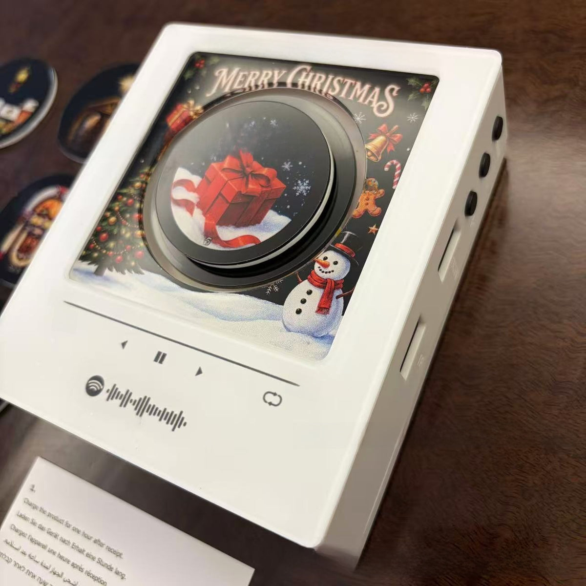 Close view of the white music player frame with a Merry Christmas red gift and snowman scene under a black disc