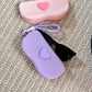 Pastel silicone sunglasses case with a raised heart on the lid and a braided wrist lanyard