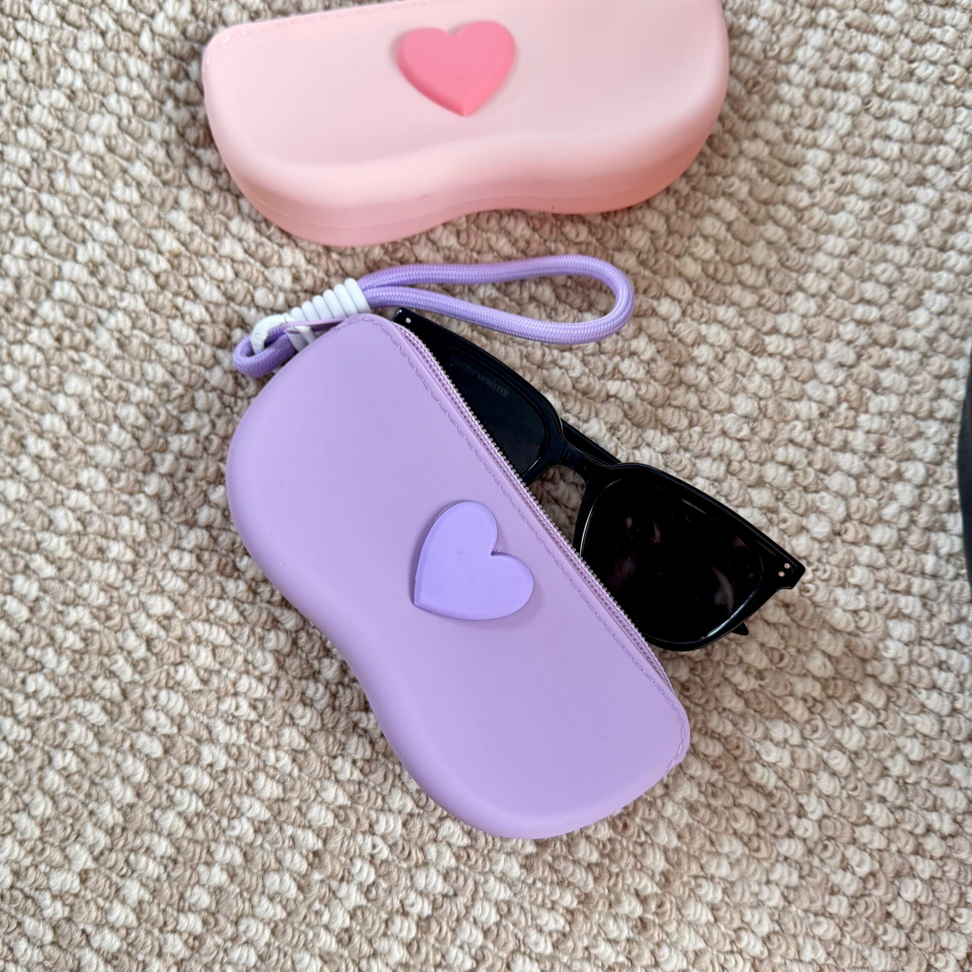 Pastel silicone sunglasses case with a raised heart on the lid and a braided wrist lanyard