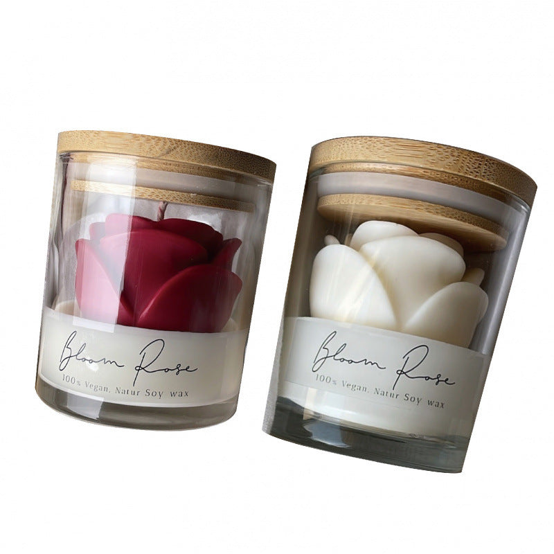 Two rose shaped candles in glass jars with bamboo lids, one red and one white, on a white background