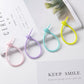 A few pastel silicone tadpole cable ties resting on open books in soft daylight
