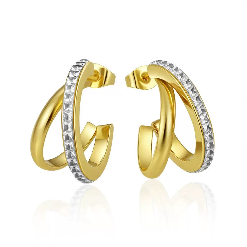 Set of coloured enamel gold plated C-shaped hoop earrings grouped on a stone tile