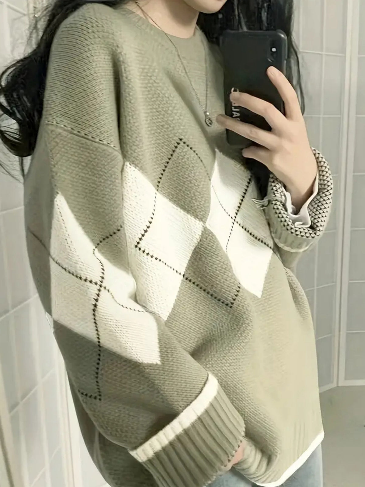 Woman in a matcha green argyle knit sweater with cream diamonds, side view in front of a mirror