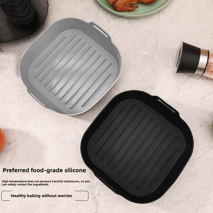 Gray and black silicone air fryer liner trays with ridged bases beside a plate of cooked bacon