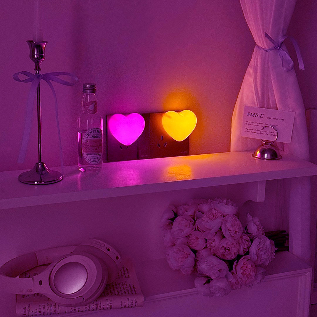 Pink and warm heart night lights glowing side by side on a shelf