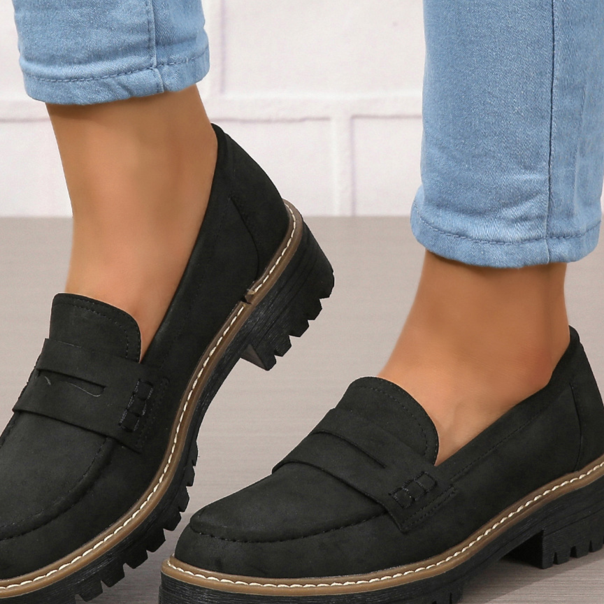 Black penny loafer with chunky rubber lug sole and heel worn with rolled light jeans