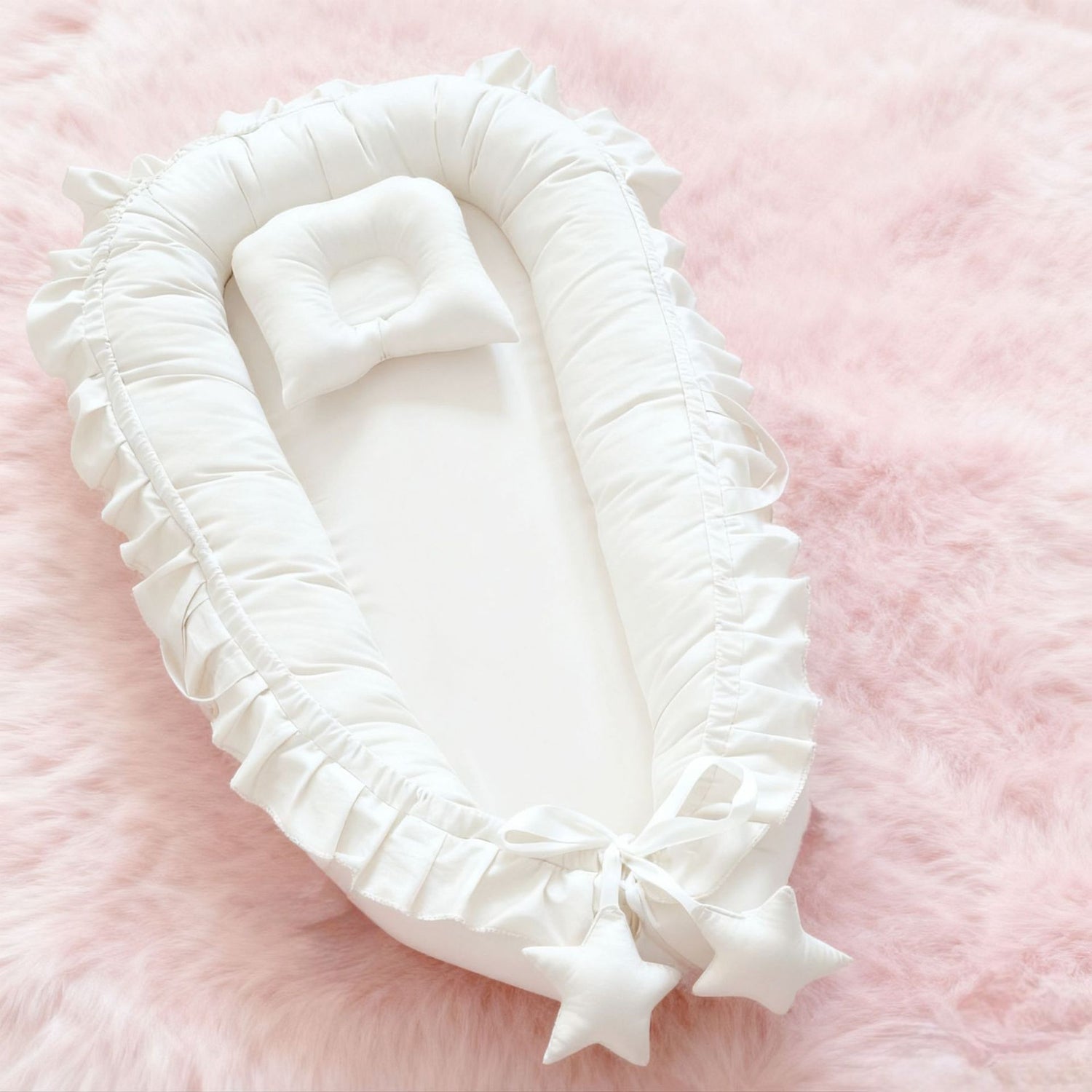 Gray cotton baby nest with a padded rim laid on a soft rug