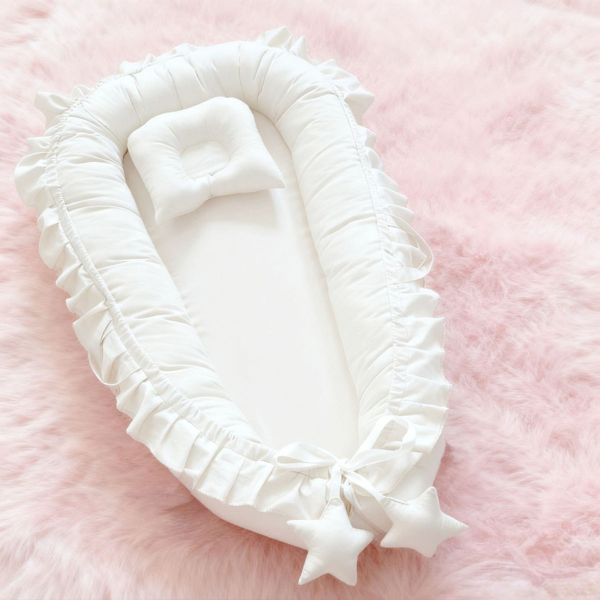 Gray cotton baby nest with a padded rim laid on a soft rug