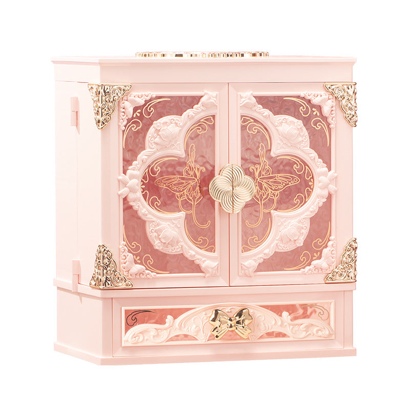 Pink makeup organizer cabinet with ornate doors and a bow drawer pull on a plain white background