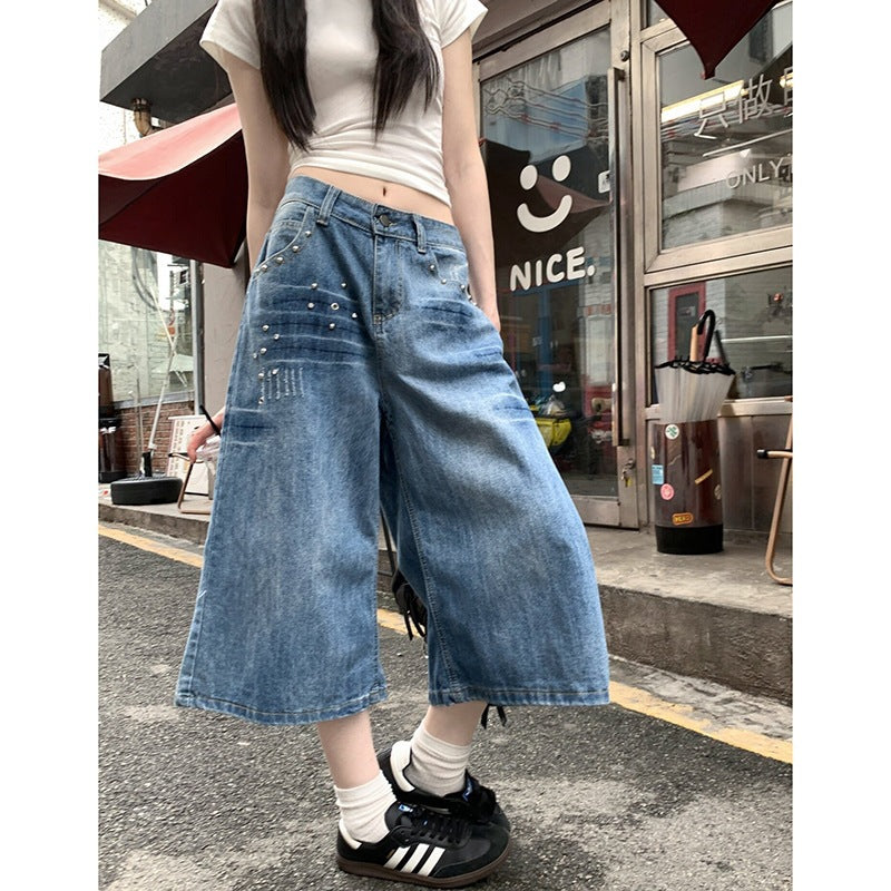 Woman in blue wide-leg cropped jeans and white tee on a street front view