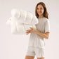 Woman holding two white puff grid bed pillows against a plain studio backdrop