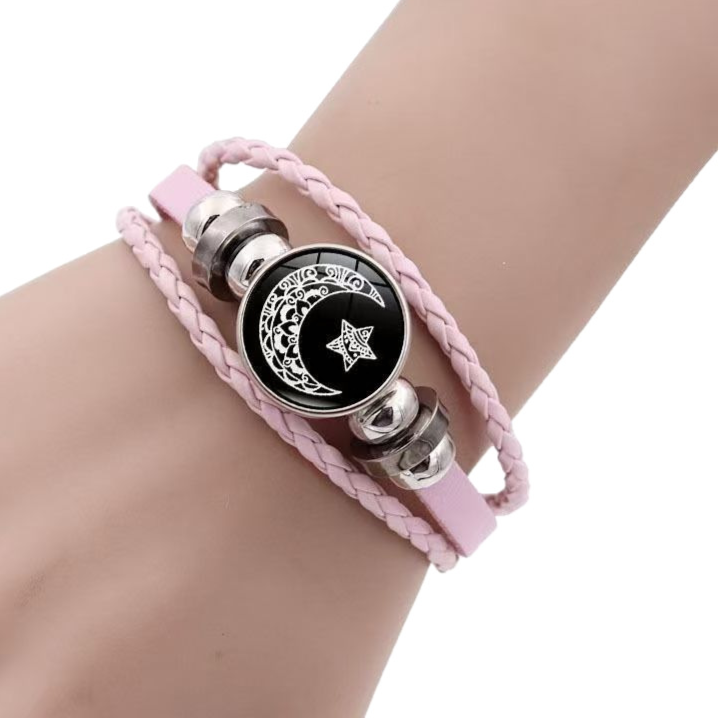 Pink braided cord bracelet on a wrist with a crescent moon and star cabochon between silver tone beads