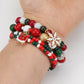 Wrist wearing a stack of red, green and white bead stretch bracelets with snowflake and bell charms
