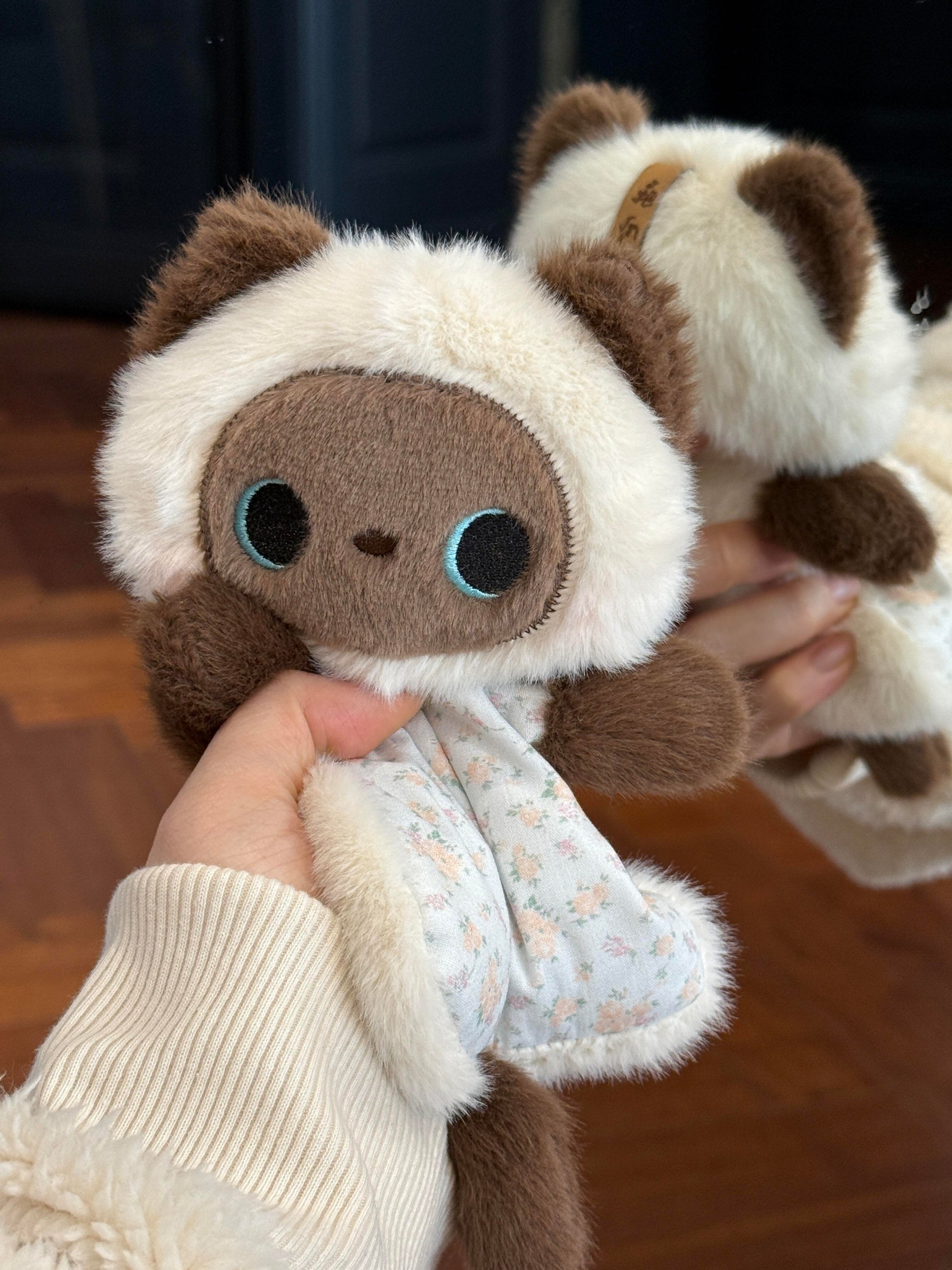 Squishy bean bag plush animal toy shown in hand, weighted body and cotton apron detail