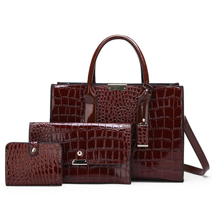 Burgundy croc pattern handbag with matching flap clutch and card wallet in a three piece set on white