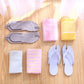 Gray flip flops folded flat beside towels on a wood floor for travel