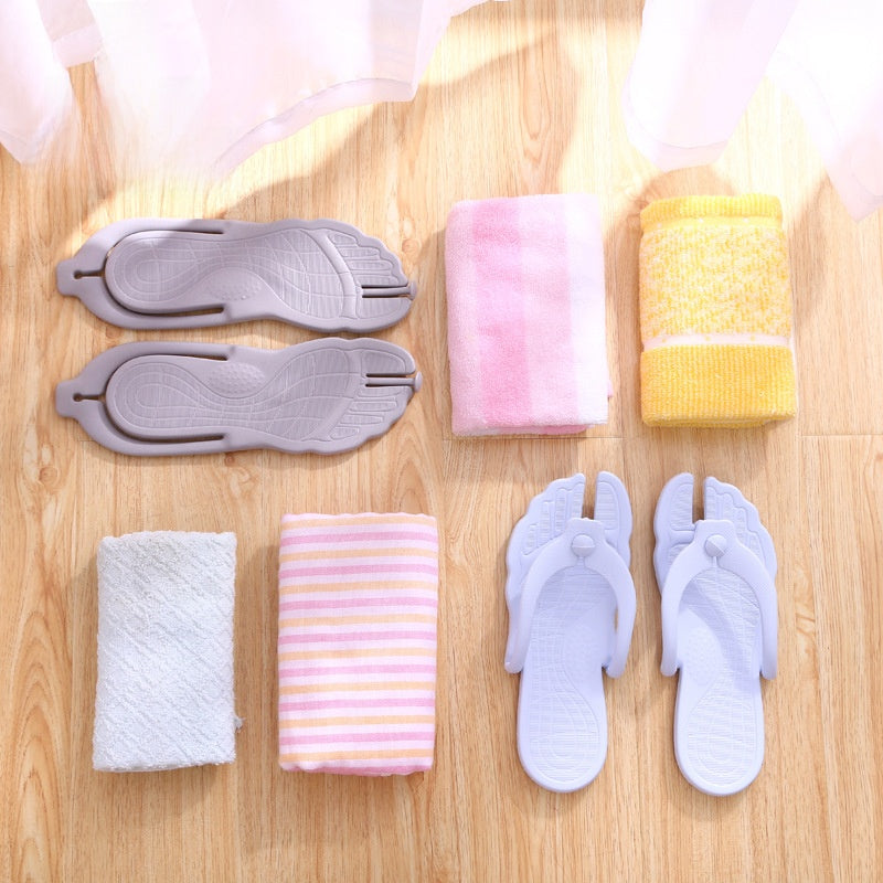 Gray flip flops folded flat beside towels on a wood floor for travel