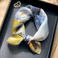 Yellow and blue floral printed square scarf with a satin sheen and hemmed edges, shown displayed