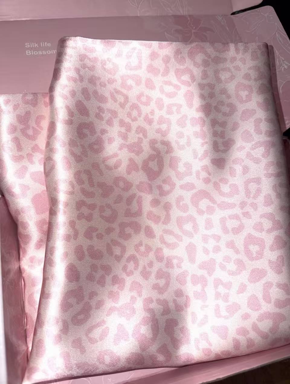 Light pink leopard silk pillowcase folded on a pink gift box