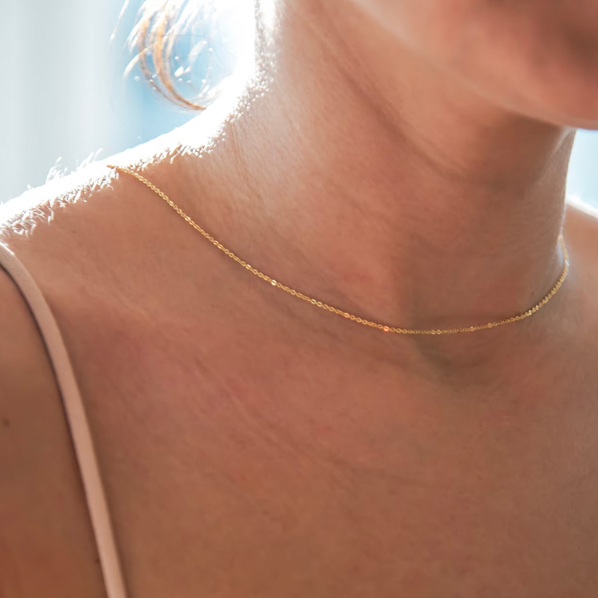 Front view of the fine gold tone chain at the collarbone