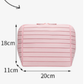 Ribbed stripe makeup organizer bag with a top handle and wrap around zip on a plain background