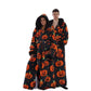 Couple in matching long black pumpkin print hooded fleece bathrobes with black plush hoods and tie belts
