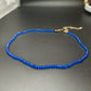 Faceted glass bead choker necklace with a gold tone chain on a plain background