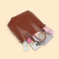 Chestnut brown leather bucket tote lying on its side with a phone, a pouch and small items beside it