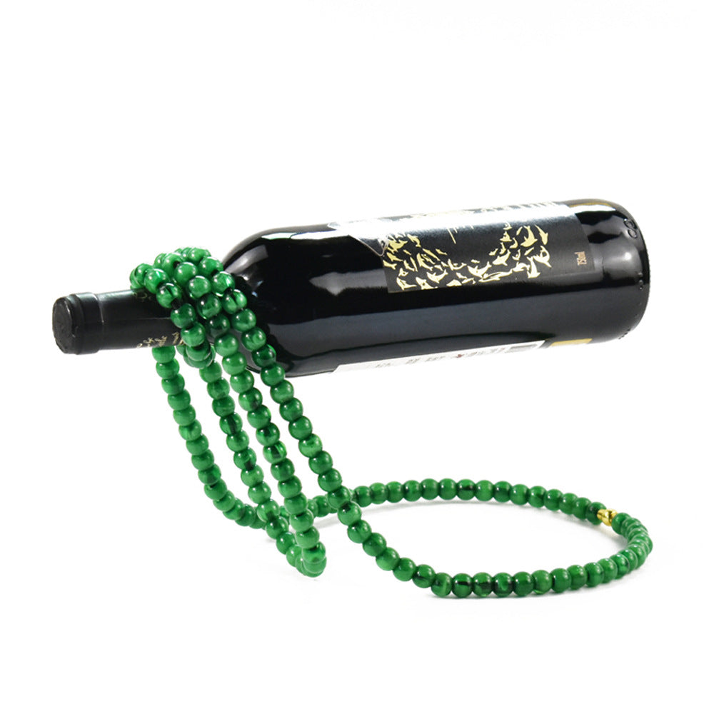 Green beaded wine bottle holder balancing a wine bottle on a white background