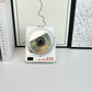 White portable CD player standing on a desk with a disc loaded under the lid