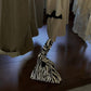 Zebra stripe triangle pouch bag with a looped handle standing on a dark wooden table