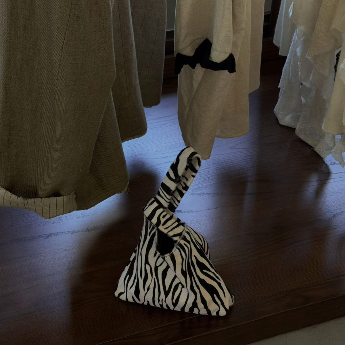 Zebra stripe triangle pouch bag with a looped handle standing on a dark wooden table